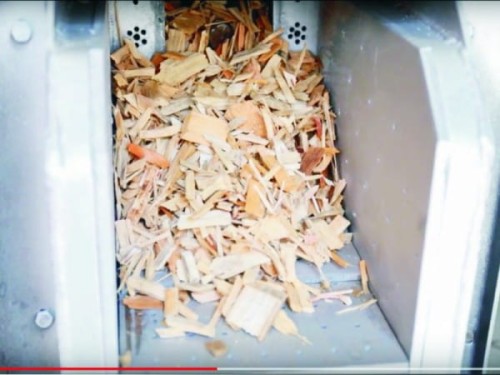 Zrębki i trociny w zasobniku palnika 150 kW do automatycznego spalania biomasy.