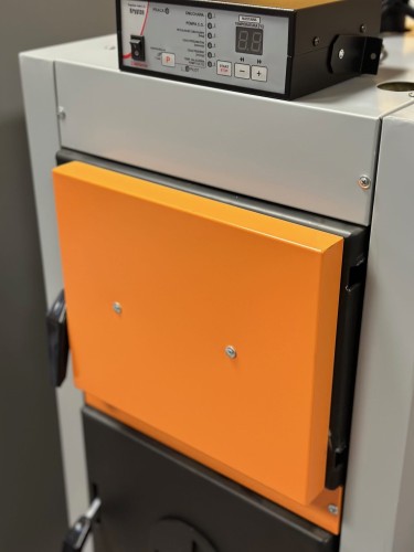 Panel sterowania kotła Ultima CMW 12-10 kW z wyświetlaczem cyfrowym i pomarańczową klapką.