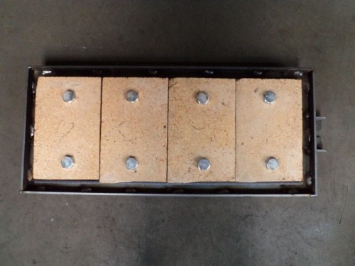 Cegła do drzwiczek (Logica 100-110) do kotła na paliwa stałe: cztery cegły szamotowe w ramie metalowej.